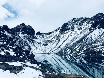 白天多云的天空下被雪覆盖的山